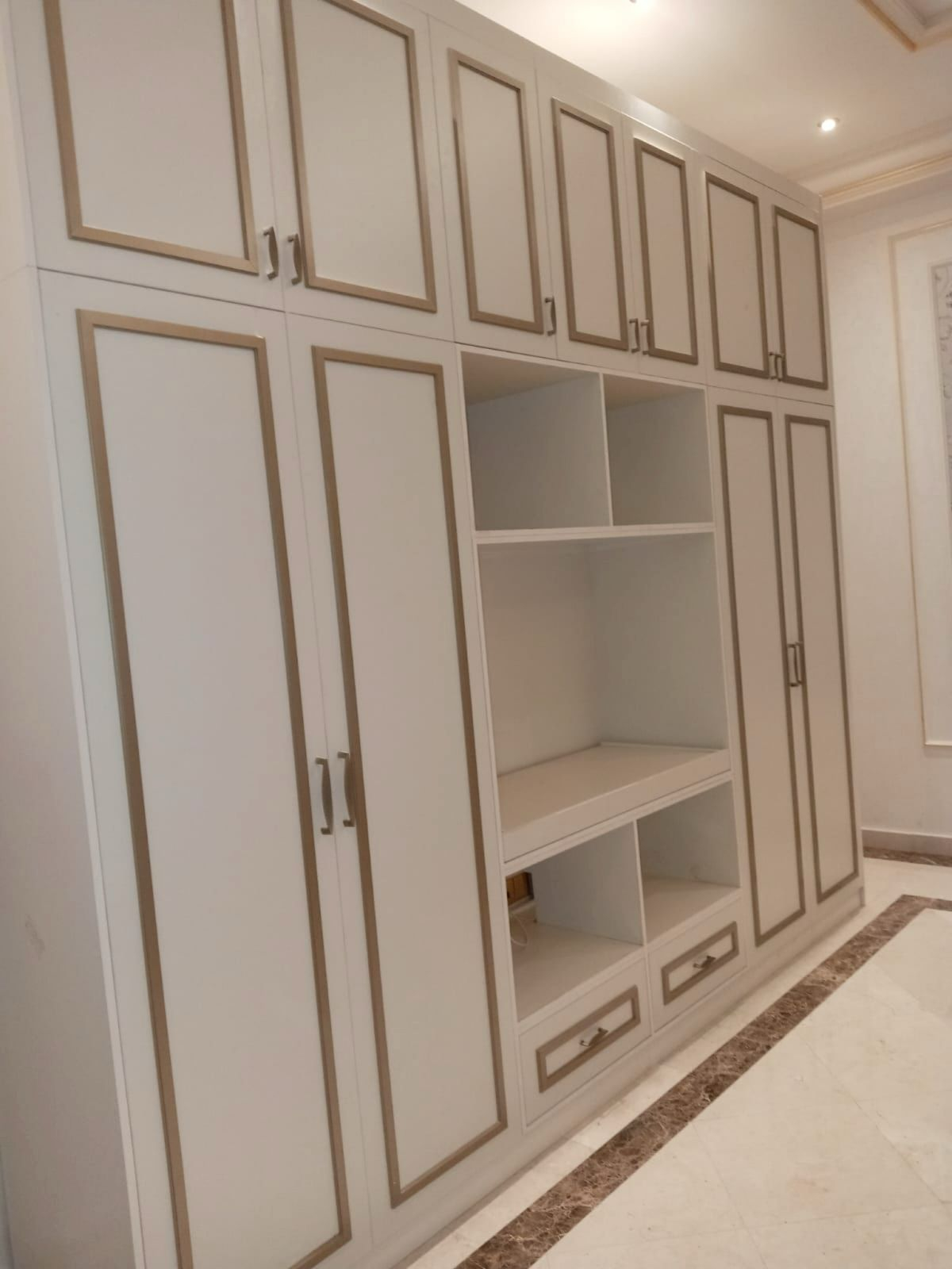 Built-in wardrobe with gold trim and open shelving — UAE villa